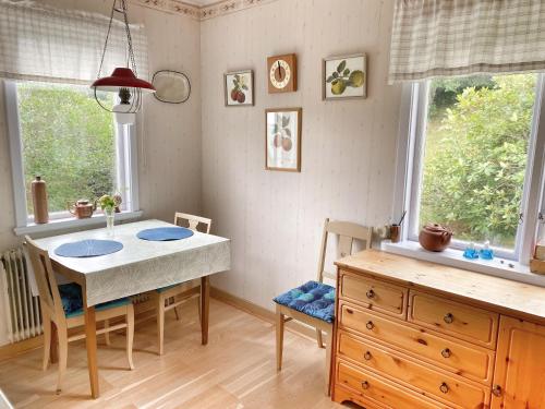 eine Küche mit einem Tisch und Stühlen sowie 2 Fenstern in der Unterkunft Cottage with sea view, Kattviksvägen in Båstad
