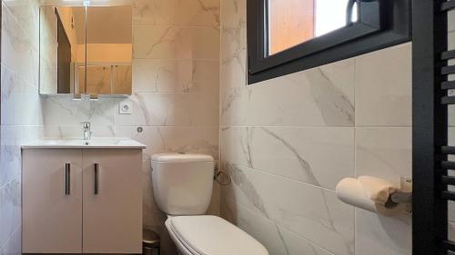 a bathroom with a toilet and a sink and a window at Chalet Anthony in Faucon-de-Barcelonnette