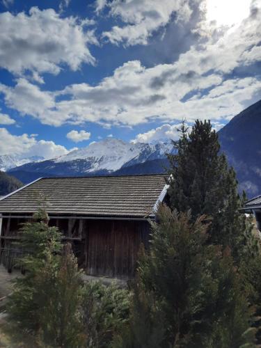 a barn with a snow covered mountain in the background at Maridl`s Ferienhaus in Umhausen