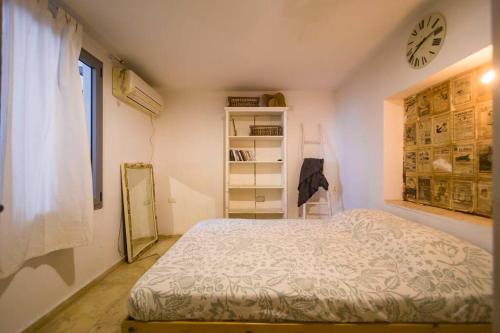 ein Schlafzimmer mit einem Bett und einer Uhr an der Wand in der Unterkunft house with patio carmel market in Tel Aviv