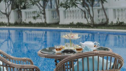a table with a tray of tea and cups next to a pool at Seaside Boutique Resort Quy Nhon in Quy Nhon