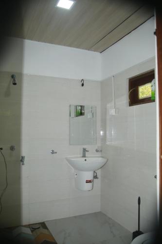a white bathroom with a sink and a shower at Shanthi Villa Resort in Anuradhapura