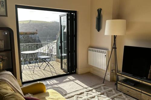 een woonkamer met een glazen schuifdeur naar een balkon bij The Captain’s 4 Bed Penthouse in Fowey