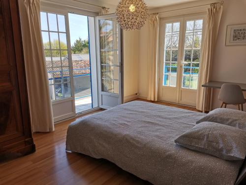 1 dormitorio con 1 cama y ventanas grandes en maison de campagne proche des plages, en Saint-Romain-de-Benet