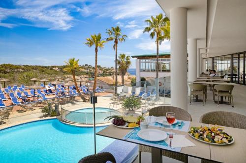 a view of the pool at a resort with a table and chairs at Flipflop Cala Mandia in Cala Romàntica