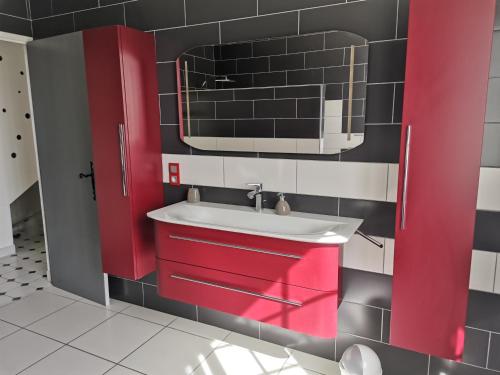 baño con armarios rojos y lavamanos en maison de campagne proche des plages, en Saint-Romain-de-Benet