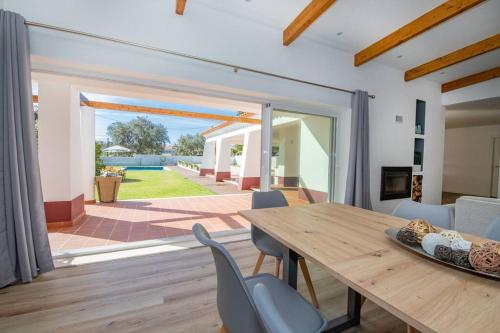 a dining room with a wooden table and chairs at Casa de campo e praia in Alfarim