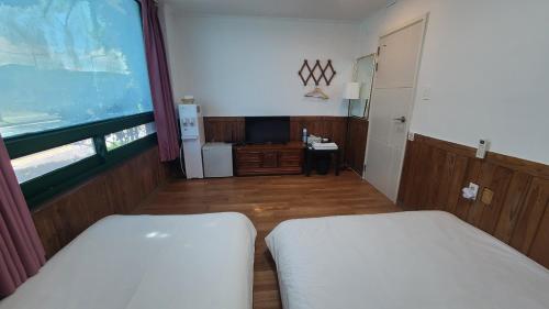a room with two beds and a large window at Bella Yuna Inn in Jeju