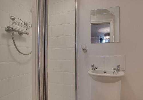 uma casa de banho com um chuveiro, um lavatório e um espelho. em Serendipity em Whitby