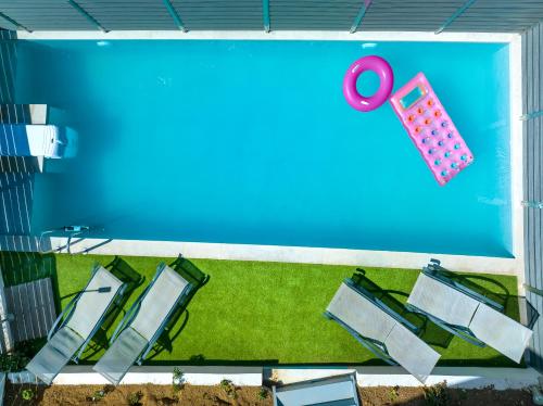 une piscine avec quatre chaises et des tongs roses dans l'établissement Creta Sun luxury apartments, à Réthymnon