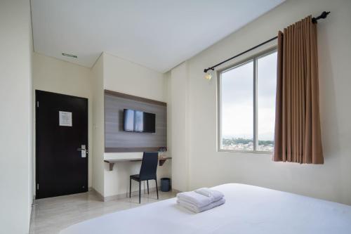 a bedroom with a bed and a desk and a window at Cove West Inn Cihampelas in Bandung