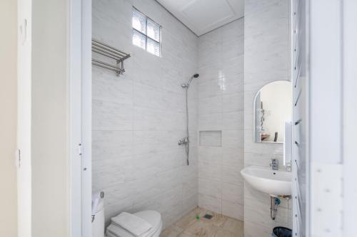 La salle de bains blanche est pourvue d'un lavabo et de toilettes. dans l'établissement Cove West Inn Cihampelas, à Bandung