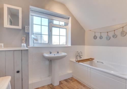 a white bathroom with a sink and a bath tub at Seashell Cottage in Whitby