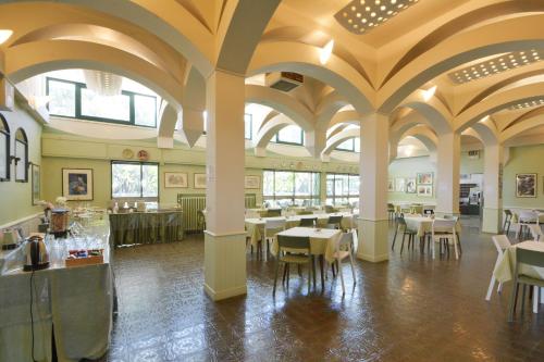 una sala da pranzo con tavoli, sedie e soffitti di Hotel Maddalena a Marina di Ravenna