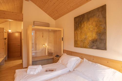 Un dormitorio con una cama blanca y una pintura en la pared en Giallo Dolomiti Wellness en Pieve di Cadore