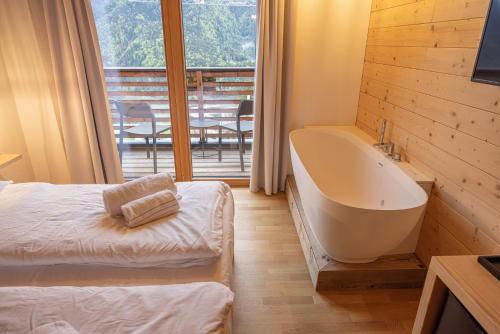 Giallo Dolomiti Wellness في بييفي دي كادوري: غرفة نوم مع حوض وسرير وشرفة