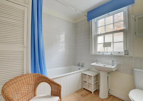 La salle de bains est pourvue d'une baignoire blanche, d'un lavabo et d'une fenêtre. dans l'établissement Seals Cottage, à Whitby
