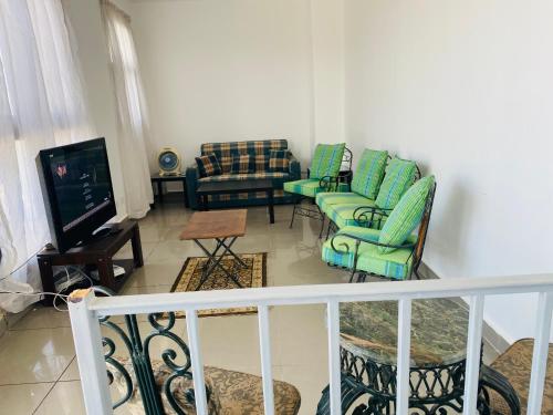 a living room with green chairs and a television at Lovely penthouse 4- bedroom directly on the lagoon in El Alamein