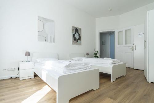 two white beds in a white room with wooden floors at Cozy Apartment in Wiesbaden in Wiesbaden