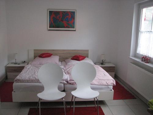 een slaapkamer met een bed en 2 witte stoelen bij Zellerhorn in Albstadt