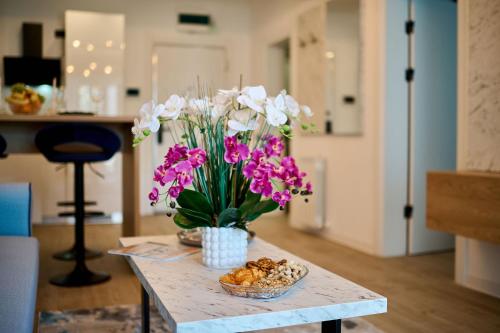 Una mesa con un jarrón de flores y galletas. en Vlezal Apartment Spa&Pool Beach Resort en Mamaia