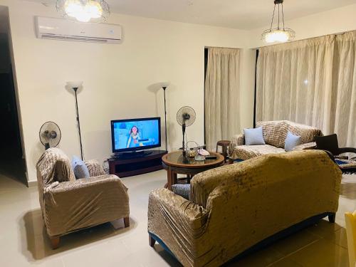 a living room with a couch and chairs and a television at Lovely penthouse 4- bedroom directly on the lagoon in El Alamein