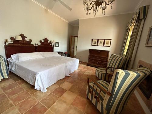 een slaapkamer met een groot bed en 2 stoelen bij La Huerta de Don Fernando in Villarrobledo