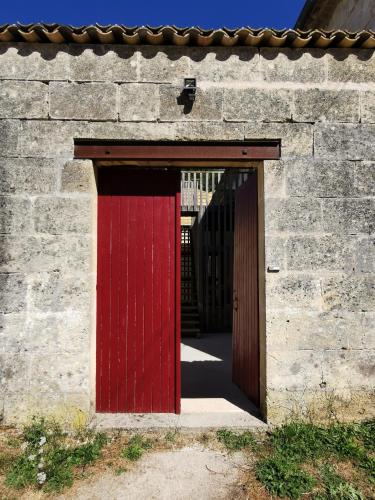 uma porta vermelha num edifício de tijolos com em Gîte de charme au cœur de l'entre-deux-mers em Haux