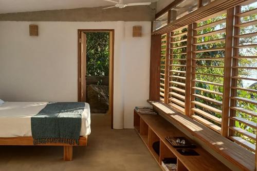 a bedroom with a bed and a large window at REFUGIO na frente do mar em Ilha de Araujo in Paraty