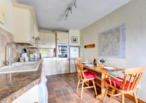 cocina con mesa de madera, sillas y encimera en Scar End Cottage en Ingleton 