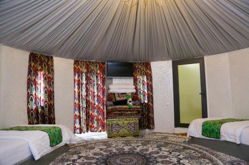 a bedroom with two beds and a window and a rug at Hotel Gumbaz in Samarkand