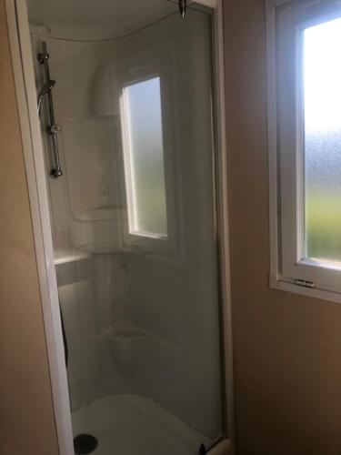 une salle de bain avec une douche en verre avec une fenêtre dans l'établissement mobilhome K69 les charmettes, aux Mathes