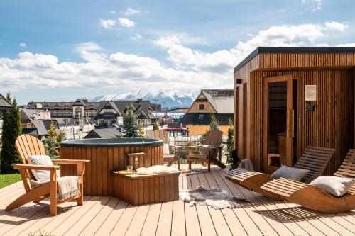 a deck with chairs and a hot tub and a building at Domki w Białce WOODHOUSE- basen, sauna, jacuzzi in Białka Tatrzanska