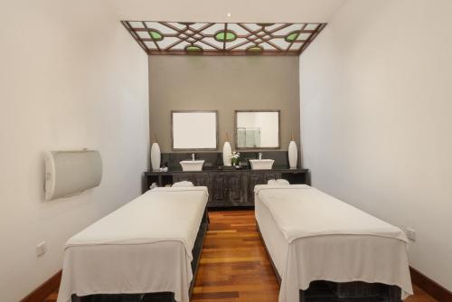 two beds in a room with two sinks and two mirrors at The Grand Hotel - Heritage Grand in Nuwara Eliya