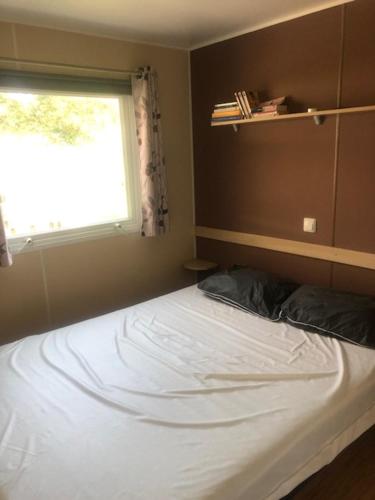 un lit dans une chambre avec une fenêtre dans l'établissement mobilhome K69 les charmettes, aux Mathes