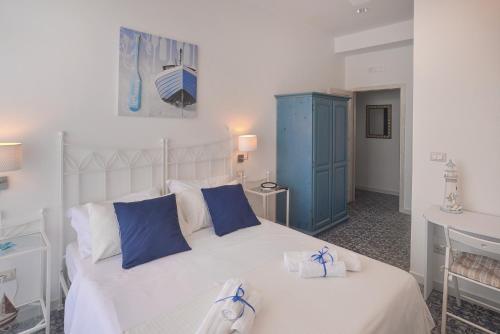 um quarto com uma cama branca e um armário azul em Hotel La Caravella em Agropoli