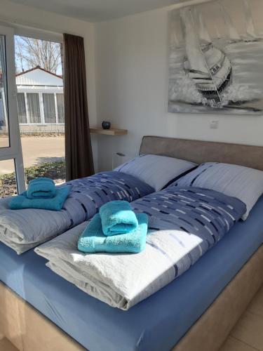 Una cama grande con toallas azules encima. en Ferienhaus am Quendorfer See Haus Nr.10, en Schüttorf