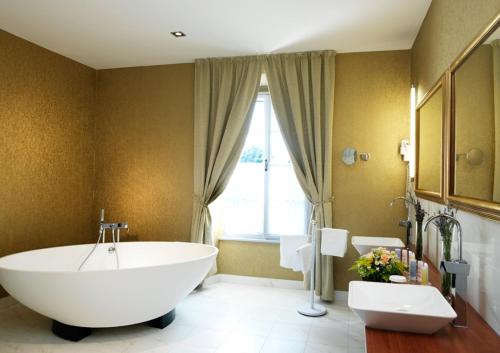 baño con una gran bañera blanca y una ventana en Hotel Convent - Hotel & Resort Adria Ankaran en Ankaran
