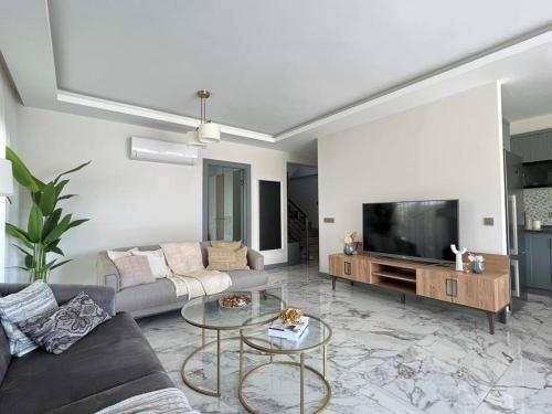 a living room with a couch and a tv at Villa Marina 4+1 Camuva in Kemer