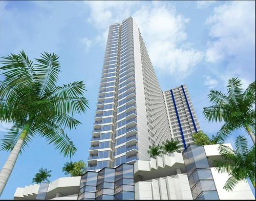 a tall white building with palm trees in front of it at Breeze Residences - 1BR Unit with Balcony -Top Floor in Manila