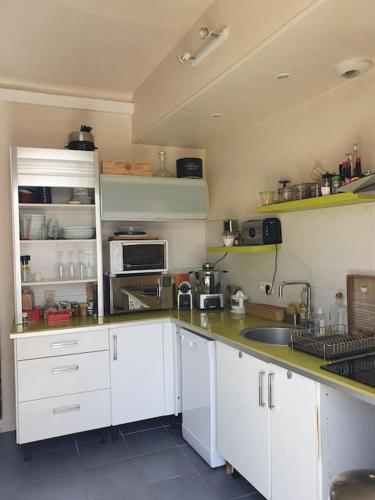 a kitchen with white cabinets and a sink at Appartement sur cour privative in Capbreton