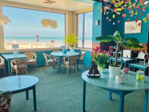 een restaurant met tafels en stoelen en het strand bij Hôtel Outre-Mer - Villa Le Couchant in Villers-sur-Mer