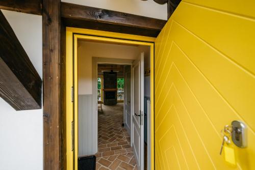 a yellow door leading into a room with a hallway at Osada Biały Wilk domek "Żółty" in Przysłup