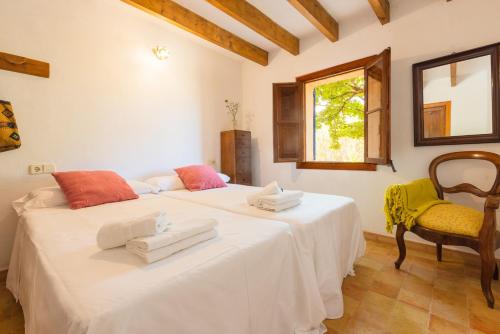 2 camas en una habitación con silla y ventana en Hortella -Ecofinca- en Sant Joan