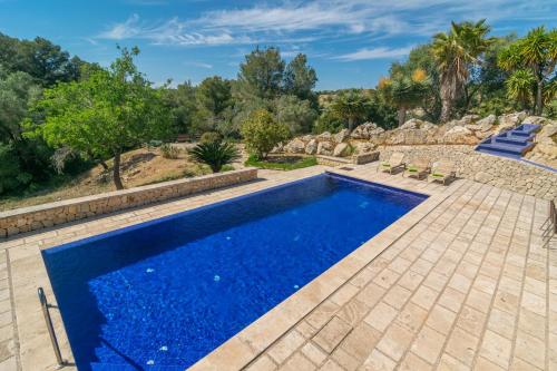 a swimming pool with blue water in a backyard with trees at Hortella -Ecofinca- in Sant Joan
