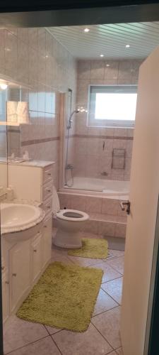 ein Badezimmer mit einem WC, einem Waschbecken und einer Badewanne in der Unterkunft Gyöngyike Apartmanház Vonyarcvashegy in Vonyarcvashegy