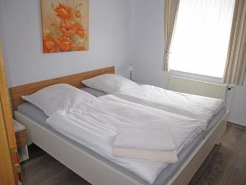 ein Bett mit weißer Bettwäsche und Kissen in einem Schlafzimmer in der Unterkunft Wohnung 2 - a66735 in Staberdorf