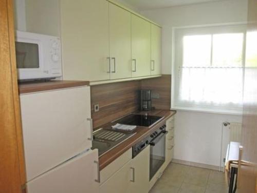 eine Küche mit einer Mikrowelle und einem Herd Top-Backofen in der Unterkunft Wohnung 2 - a66735 in Staberdorf