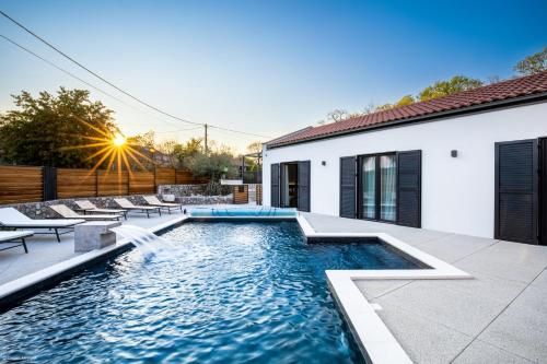 a swimming pool with chairs and a house at Villa Primus in Gostinjac
