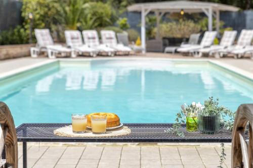 a table with two drinks and a cake next to a swimming pool at Villa Matian in Marina di Sorso